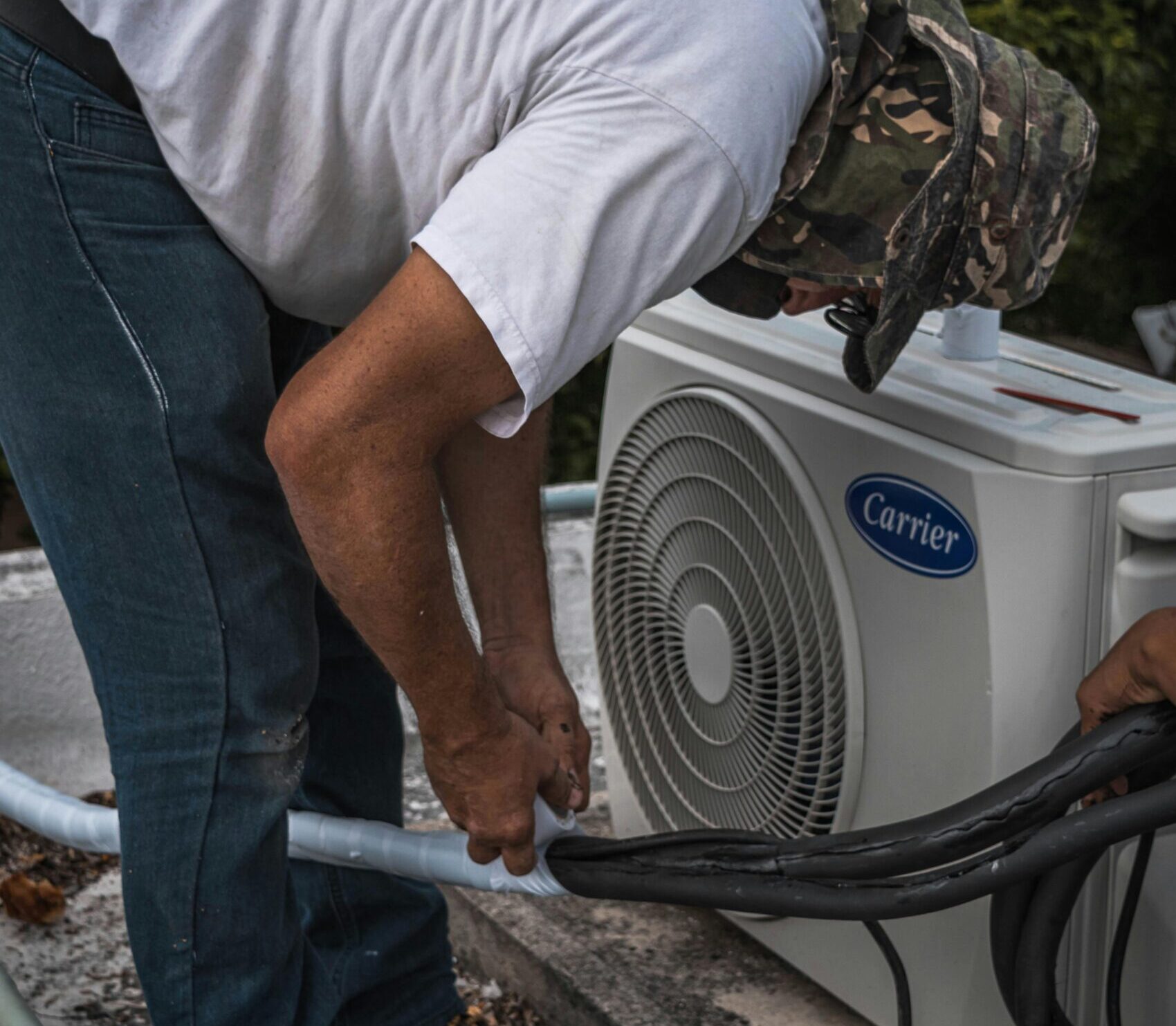 pexels-photo-5463576-5463576 A technician performs maintenance on an outdoor air conditioning unit, focusing on hose connections.